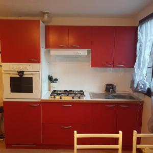 een keuken met rode kasten en een fornuis met oven bij Superbe studio dans la vallée de l'Eau d'Olle. in Allemont