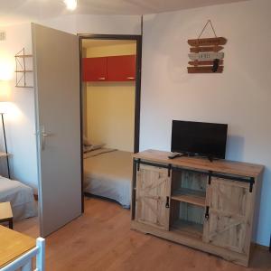 een kamer met een tv op een kast en een slaapkamer bij Superbe studio dans la vallée de l'Eau d'Olle. in Allemont