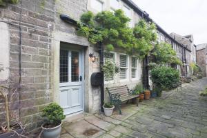 ein Backsteingebäude mit einer weißen Tür und einer Bank in der Unterkunft Weavers Retreat by Weavers of Haworth in Haworth