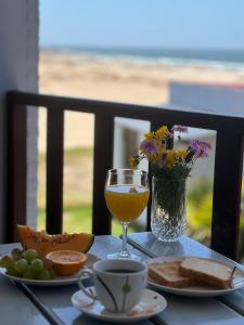 a table with a glass of wine and a vase of flowers at El Diablo Chic Colonial in Punta Del Diablo