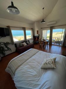 a bedroom with a white bed with a view of the ocean at El Diablo Chic Colonial in Punta Del Diablo