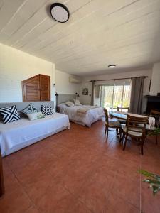 1 dormitorio con 2 camas, mesa y sillas en El Diablo Chic Colonial, en Punta del Diablo