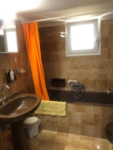 a bathroom with an orange curtain and a sink at Lemon tree's house in Kalavárda