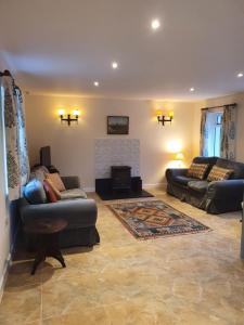 a living room with two couches and a fireplace at Villa Muneera - rural retreat in the heart of Pembrokeshire in Narberth