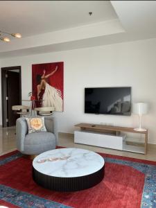 sala de estar con TV grande y mesa de centro circular. en Stylish One bedroom with all amenities, close to downtown1, en Dubái