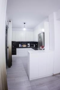 eine Küche mit weißen Schränken und einem Kühlschrank aus Edelstahl in der Unterkunft GRANDE APARTMENT KORCE in Korçë