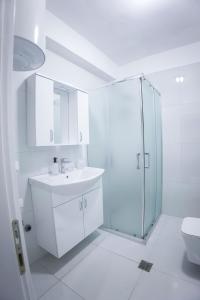 een witte badkamer met een douche en een wastafel bij GRANDE APARTMENT KORCE in Korçë
