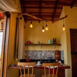 a kitchen with two chairs and a counter with lights at Espaço Canela-de-Ema in Alto Paraíso de Goiás