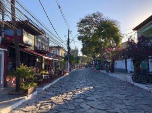 una calle adoquinada en una ciudad con gente caminando por ella en Búzios Conforto Guest House - 450 metros Rua das Pedras, en Búzios