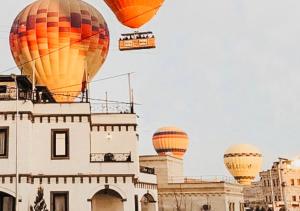 een groep heteluchtballonnen die over een gebouw vliegen bij Osmanli Cappadocia Hotel in Goreme