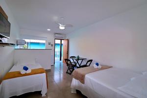 a hotel room with two beds and a table at Búzios Conforto Guest House in Búzios