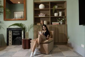 une femme assise sur une chaise en lisant un livre dans l'établissement The Pacific House, à Sydney