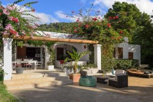 Villa Can Cozy في مدينة إيبيزا: منزل مع فناء مع مجموعة من الزهور
