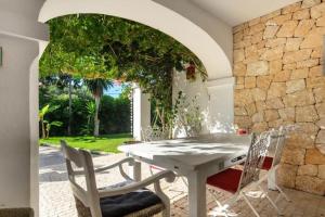 Villa Can Cozy في مدينة إيبيزا: طاولة بيضاء وكراسي في فناء بجدار حجري