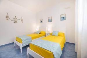 two beds in a room with yellow and blue at Belvedere Apartments B in Marina di Mancaversa