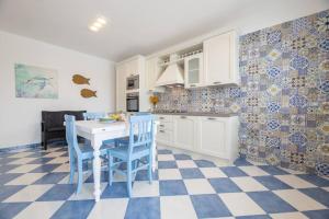 a kitchen with a white table and blue chairs at Belvedere Apartments B in Marina di Mancaversa +7 photos