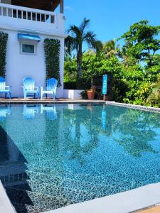 a swimming pool with chairs and a house at Serenity Rincon Guesthouse in Rincon