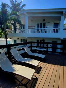 una terraza con tumbonas y palmeras en una casa en Serenity Rincon Guesthouse, en Rincón
