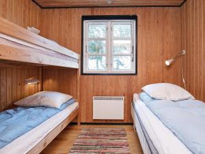two beds in a room with wooden walls and a window at Holiday home Hvide Sande XIX in Hvide Sande