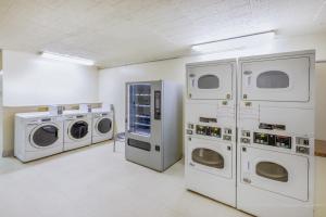a laundry room with four machines and a white wall at Baymont by Wyndham Laredo in Laredo