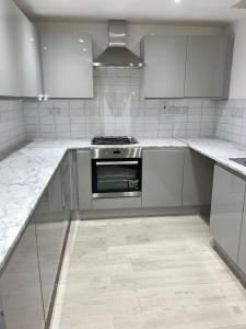 uma cozinha com armários brancos e um fogão em Archway Apartment em Londres