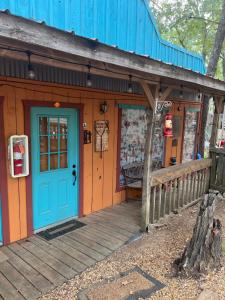 un magasin avec une porte bleue et une véranda en bois dans l'établissement Acorn Hideaways Canton Old Western Ranch Hands' Suite, à Canton