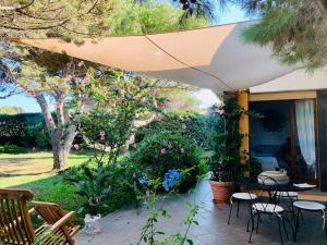 patio ze stołem i krzesłami pod parasolem w obiekcie Villa Fronte Mare w mieście Stintino