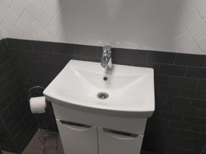 a white sink in a bathroom with black tiles at NEW апартаменты на Гвардейской in Uzhhorod