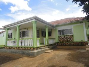 a green and white house with a porch at Larry's Place in Kampala