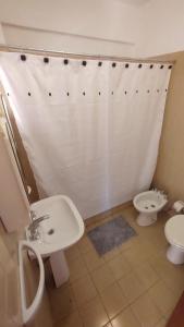 y baño con cortina de ducha blanca y aseo. en CONFORTABLE DEPARTAMENTO CÉNTRICO en Salta