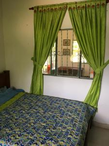 1 dormitorio con 1 cama y una ventana con cortinas verdes en Finca La Belleza-Villeta, en Villeta