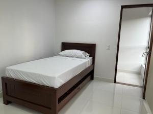 Cama en habitación blanca con suelo blanco en Hotel Plaza Berlín, en Medellín