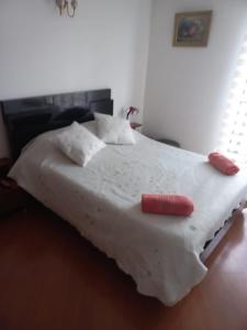 ein weißes Bett mit einem roten Objekt darüber in der Unterkunft APARTA-HOTEL BADEN in Bogotá