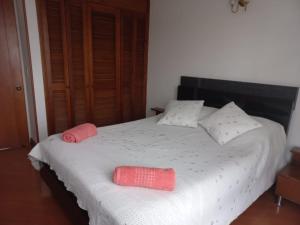 um quarto com uma cama branca com duas almofadas em APARTA-HOTEL BADEN em Bogotá