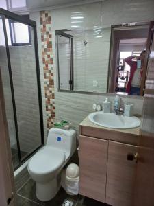 a bathroom with a toilet and a sink and a mirror at APARTA-HOTEL BADEN in Bogotá