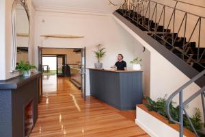 a woman sitting at a counter in a room with a staircase at Sports Garden Hotel in Launceston