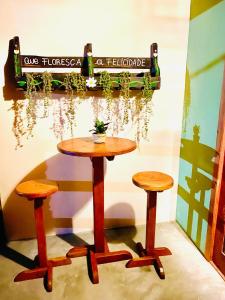 una mesa y dos taburetes delante de una pared en Carpe Diem Suítes Taipu de Fora, en Maraú
