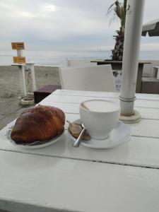 Una mesa con una taza de café y un pastel. en Triremi house, en Lido di Ostia