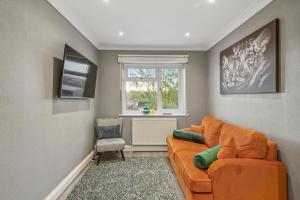 a living room with an orange couch and a window at Cosy home in Rochester, sleeps 6 in Strood