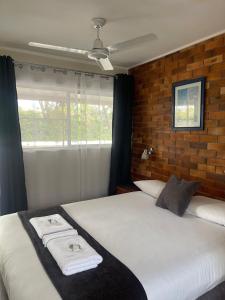 a bedroom with two beds and a brick wall at Avocado Motor Inn in Childers