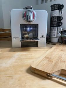 a toaster sitting on top of a table with a cutting board at Appartement paisible proche centre ville in Villennes-sur-Seine