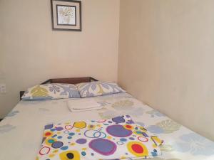 uma cama com lençóis e almofadas floridos em Casa Sarmiento Travellers Inn em Laoag