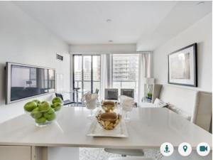 a white dining room with a table with a bowl of fruit at Comfortable Central Downtown Condo - in Toronto
