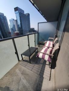uma varanda com uma cama e uma cadeira num edifício em Comfortable Central Downtown Condo - em Toronto