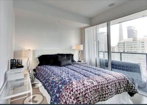 um quarto com uma cama e uma grande janela em Comfortable Central Downtown Condo - em Toronto