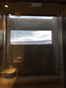 uma casa de banho com uma janela de vidro e um lavatório. em bunker em San Pedro