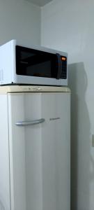 a microwave sitting on top of a white refrigerator at Casa agradável, ampla com estacionamento in Tramandaí