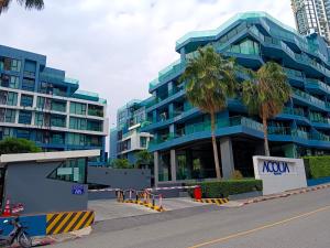 a blue building with palm trees in front of it at Acqua Condominium Jomtien in Jomtien Beach