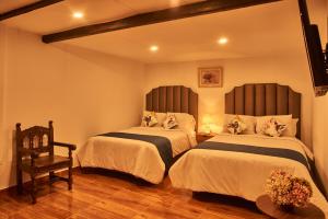 a bedroom with two beds and a chair at Hotel Dordéan Casona Boutique in Chachapoyas