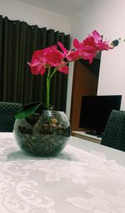 um vaso com uma flor rosa em cima de uma mesa em Apartamento inteiro próximo à Miguel Sutil em Cuiabá